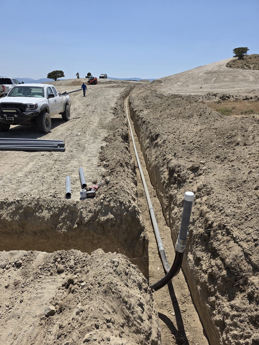Conduit sweep rising out of an open trench on a rural Utah site