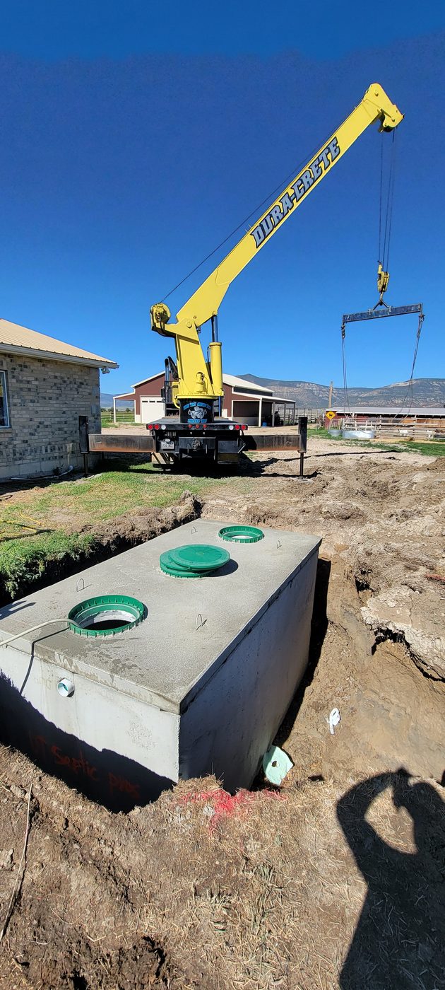 Dura-Crete boom truck setting a precast concrete septic tank on a rural Utah property