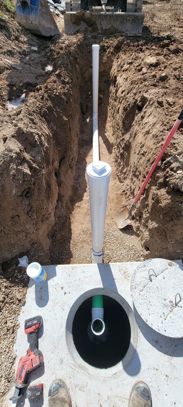 Looking down into a septic tank lid at the inlet tee with the sewer line from the house running into the trench