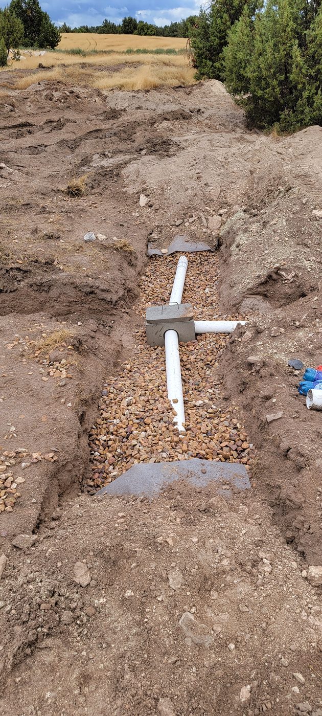 Concrete distribution box set on gravel with PVC laterals branching to the drain field trenches
