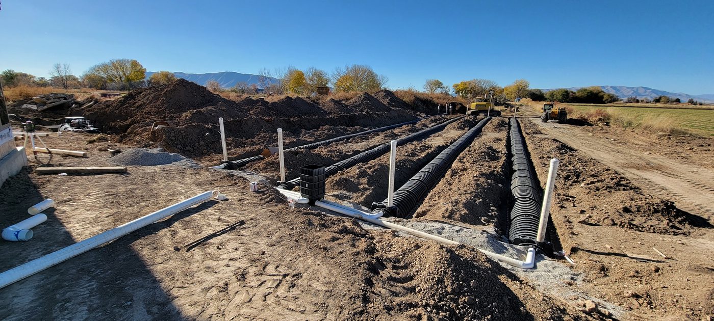 Chambered septic drain field trenches under construction with an excavator, rural Utah