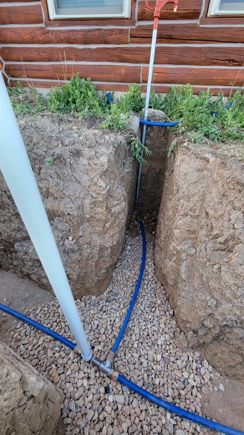 Stop and waste valve and yard hydrant installation in a gravel-bedded trench beside a log home, rural Utah