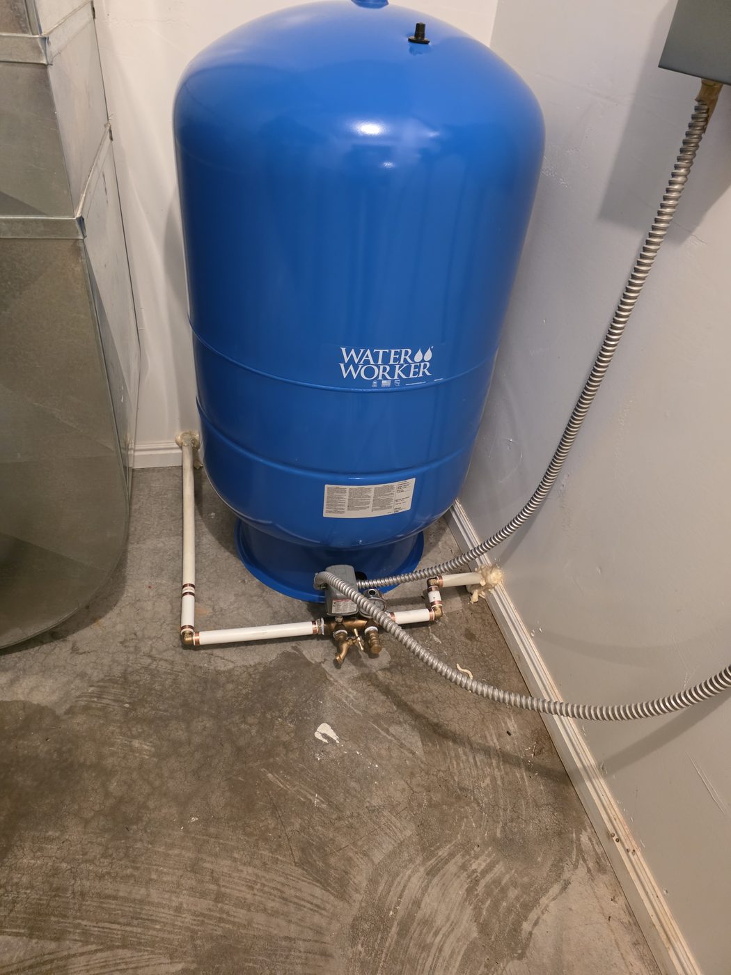 Installed well pressure tank with pressure switch and copper piping in a finished mechanical room